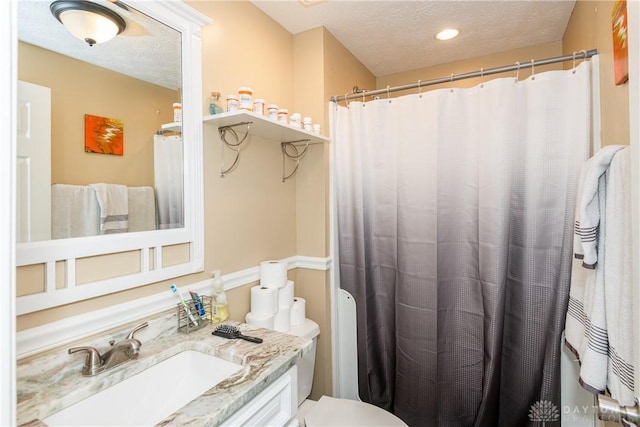 bathroom with vanity, toilet, and a textured ceiling