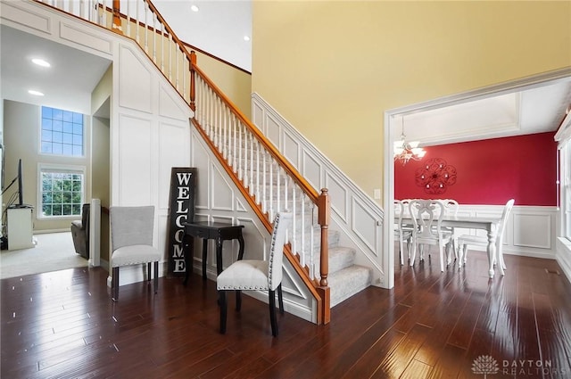 stairs with a high ceiling, a notable chandelier, and hardwood / wood-style floors