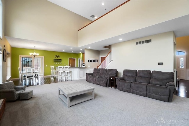 living room featuring carpet flooring, a high ceiling, and an inviting chandelier