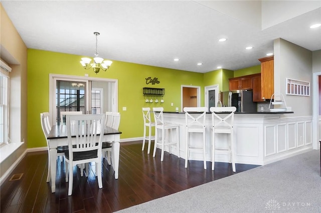 dining area with dark hardwood / wood-style floors and an inviting chandelier