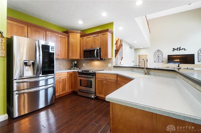 kitchen featuring kitchen peninsula, decorative backsplash, stainless steel appliances, dark wood-type flooring, and sink