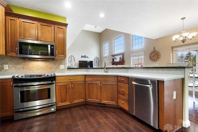 kitchen with stainless steel appliances, tasteful backsplash, dark hardwood / wood-style floors, a notable chandelier, and decorative light fixtures