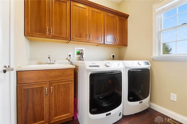 laundry room featuring washing machine and clothes dryer, dark hardwood / wood-style flooring, sink, and cabinets