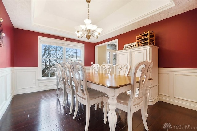 dining room with a tray ceiling, dark hardwood / wood-style floors, and a notable chandelier