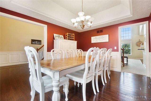 dining space with an inviting chandelier, dark hardwood / wood-style flooring, ornamental molding, and a tray ceiling