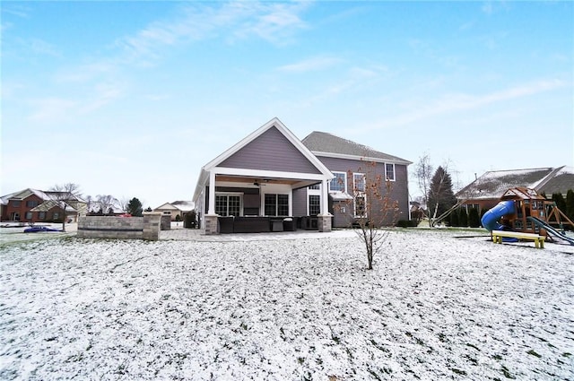 snow covered rear of property featuring a playground and ceiling fan