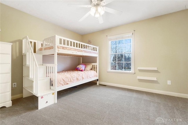 unfurnished bedroom with ceiling fan, dark colored carpet, and baseboards