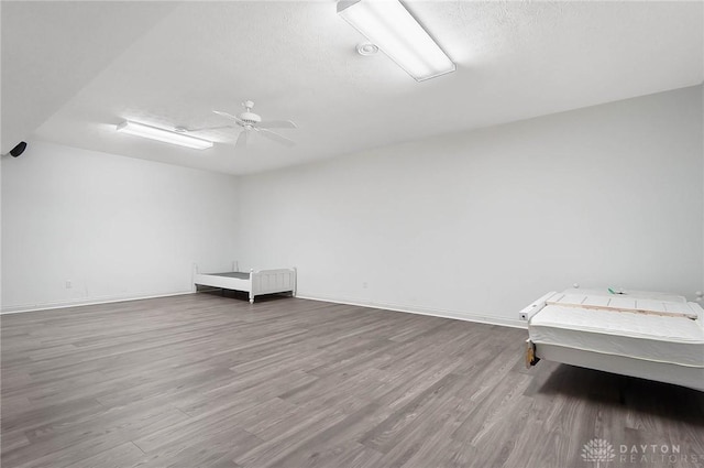 bedroom featuring a textured ceiling, light wood finished floors, a ceiling fan, and baseboards