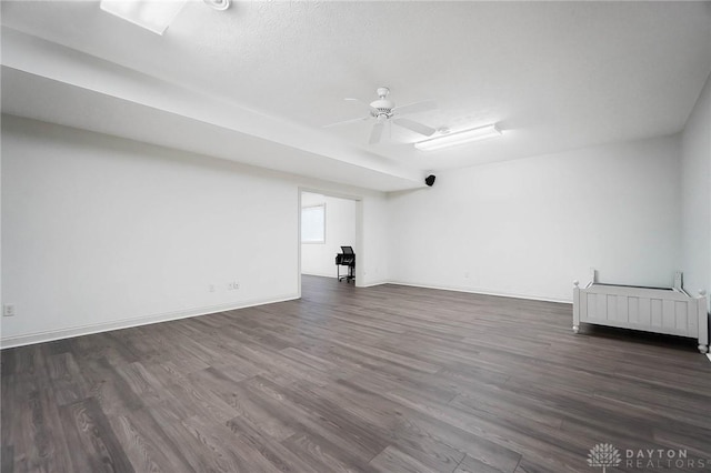 unfurnished room with dark wood-type flooring, radiator, ceiling fan, and baseboards