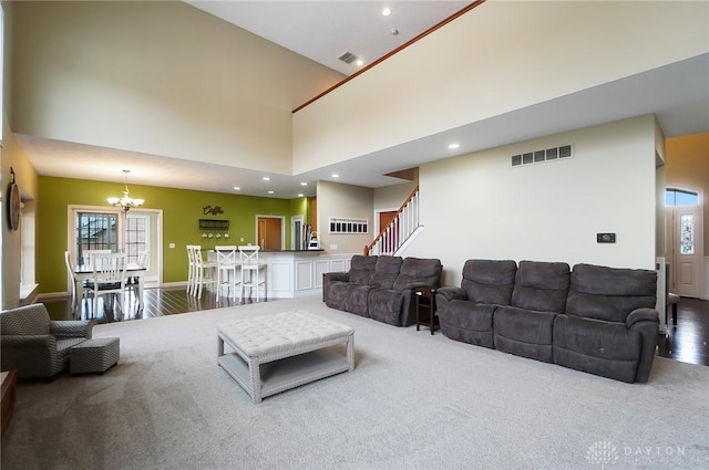 living room featuring visible vents, a high ceiling, stairs, a notable chandelier, and recessed lighting