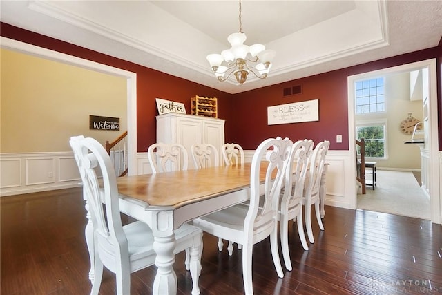 dining area with an inviting chandelier, visible vents, a tray ceiling, and dark wood finished floors