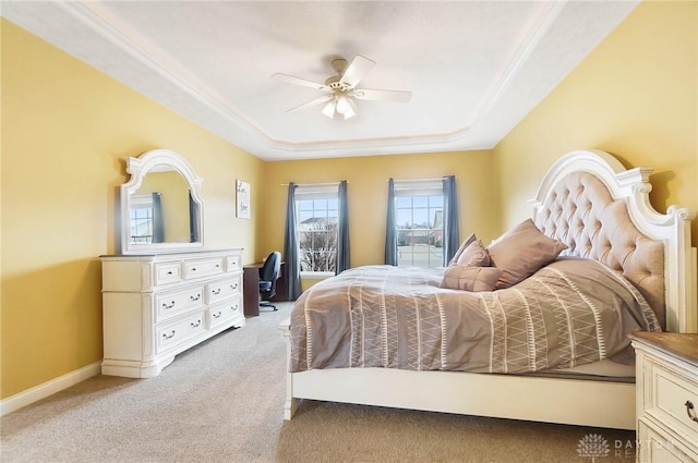 bedroom featuring light carpet, a ceiling fan, baseboards, a tray ceiling, and crown molding