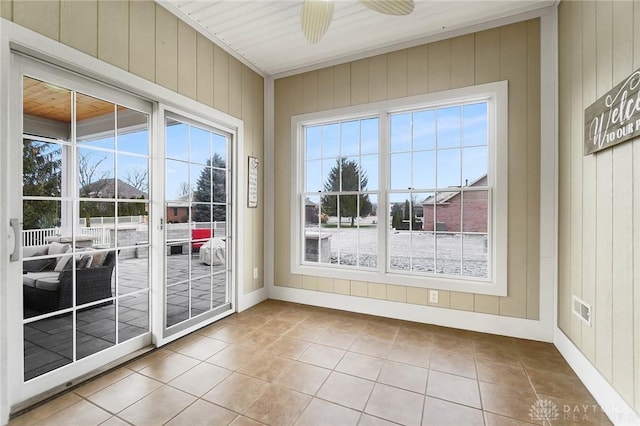 entryway featuring plenty of natural light, ceiling fan, wooden walls, and tile patterned flooring