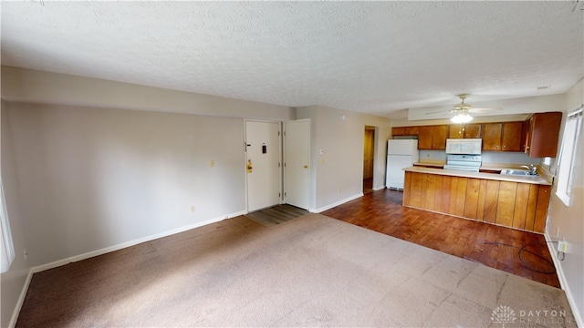 kitchen with kitchen peninsula, a textured ceiling, white appliances, sink, and dark colored carpet