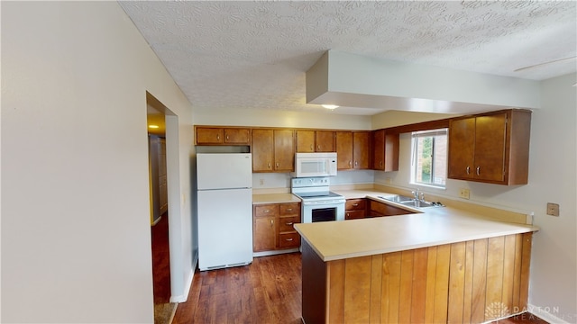 kitchen featuring kitchen peninsula, a textured ceiling, white appliances, dark wood-type flooring, and sink