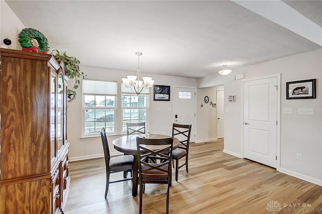 dining space with light wood-type flooring and a notable chandelier