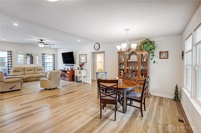 dining space with ceiling fan with notable chandelier and light wood-type flooring