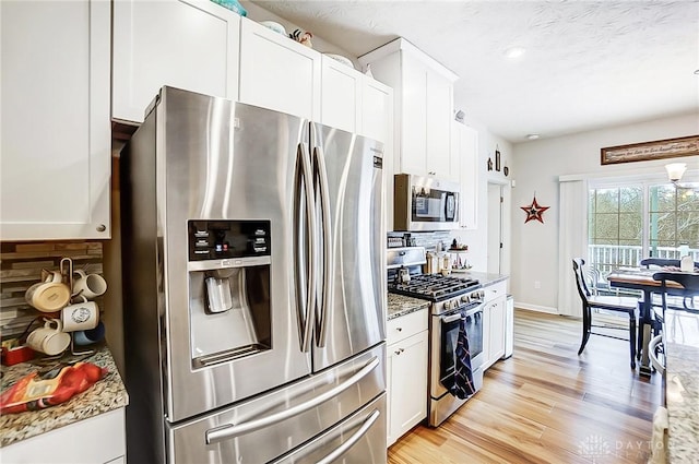 kitchen featuring light stone countertops, backsplash, stainless steel appliances, and white cabinets