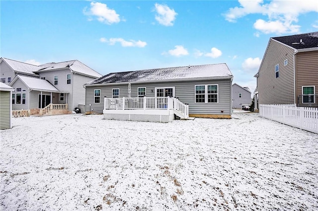 snow covered back of property with a deck