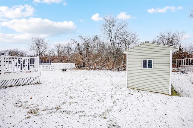 yard covered in snow with a wooden deck and an outbuilding