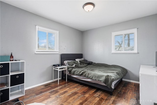 bedroom with multiple windows and dark hardwood / wood-style flooring