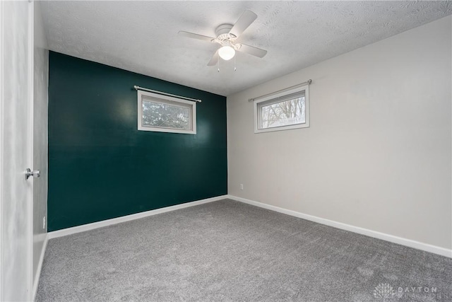 carpeted empty room featuring ceiling fan and a textured ceiling