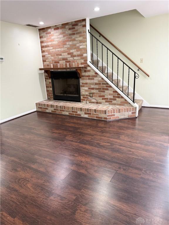 unfurnished living room featuring dark hardwood / wood-style flooring and a brick fireplace