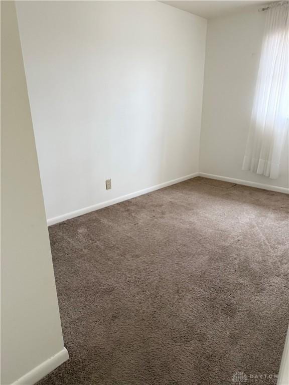 spare room with dark carpet