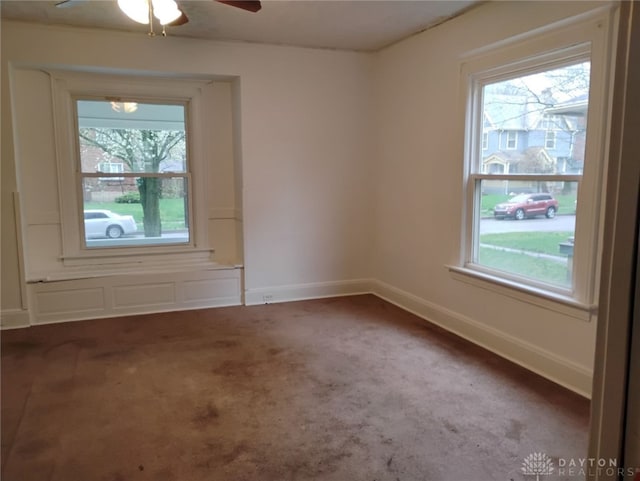carpeted empty room featuring plenty of natural light, a ceiling fan, and baseboards