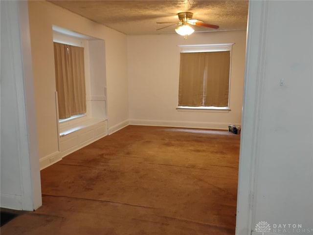 spare room featuring a textured ceiling, ceiling fan, and baseboards