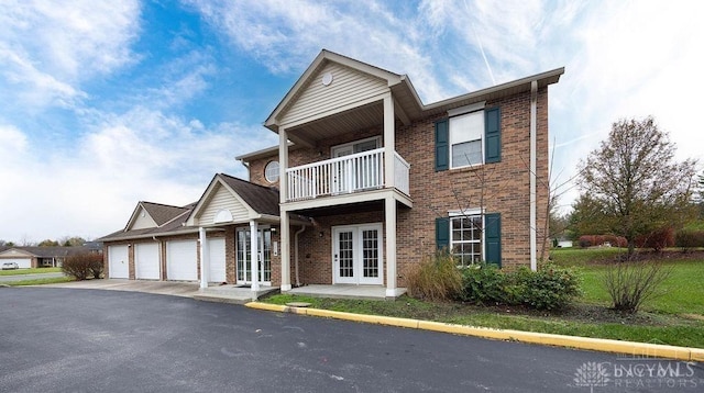 view of front of home featuring french doors, a balcony, and a garage