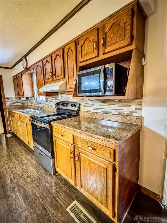 kitchen featuring dark wood-type flooring, sink, appliances with stainless steel finishes, and tasteful backsplash