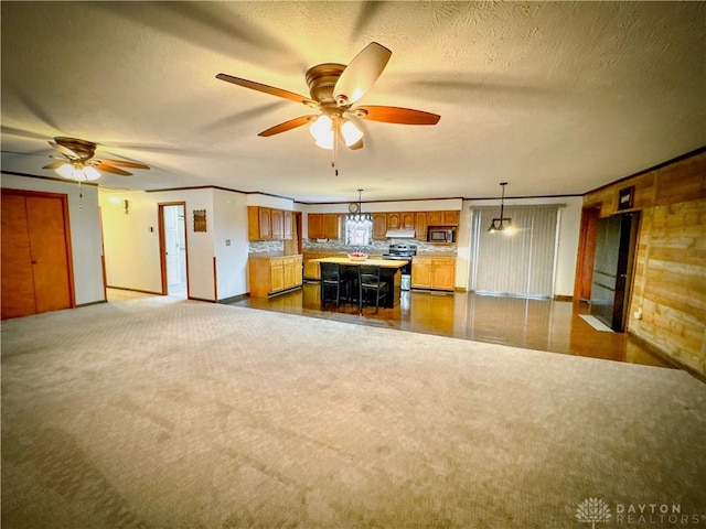 unfurnished living room with dark colored carpet, a textured ceiling, and ceiling fan