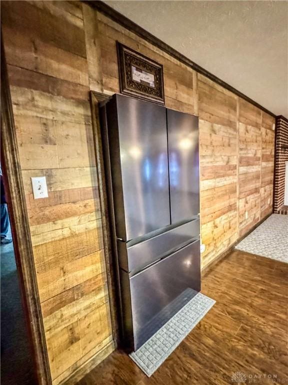 room details with stainless steel refrigerator, wooden walls, and hardwood / wood-style floors