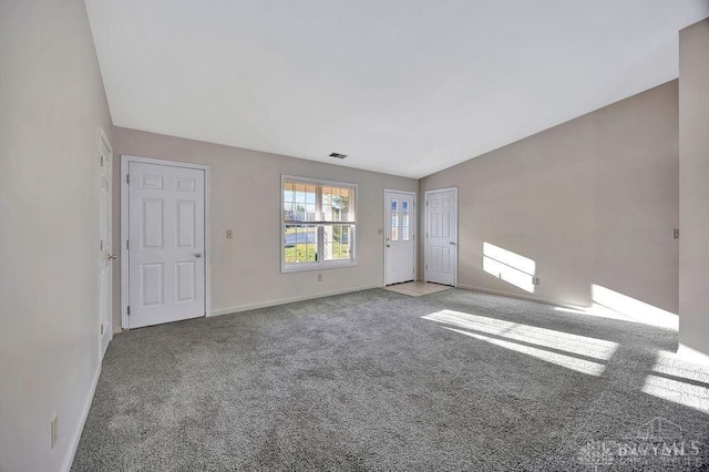 unfurnished living room with vaulted ceiling, carpet flooring, visible vents, and baseboards