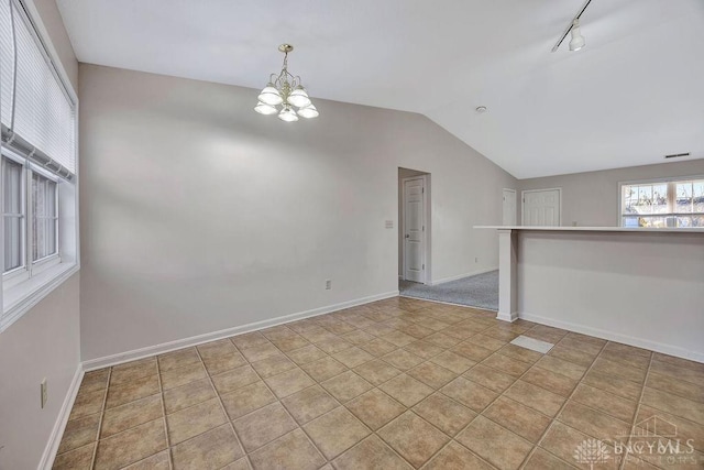 spare room featuring rail lighting, visible vents, vaulted ceiling, a chandelier, and baseboards