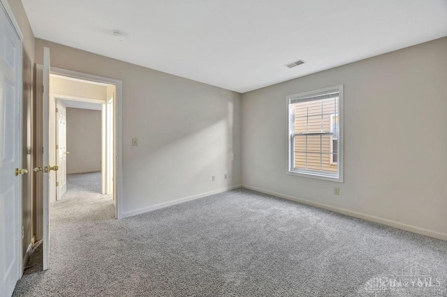 empty room featuring carpet flooring, visible vents, and baseboards