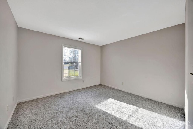 carpeted spare room featuring visible vents and baseboards