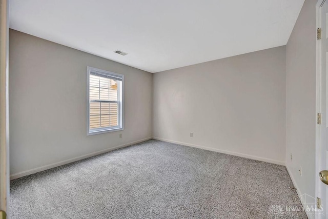 unfurnished room with carpet, visible vents, and baseboards