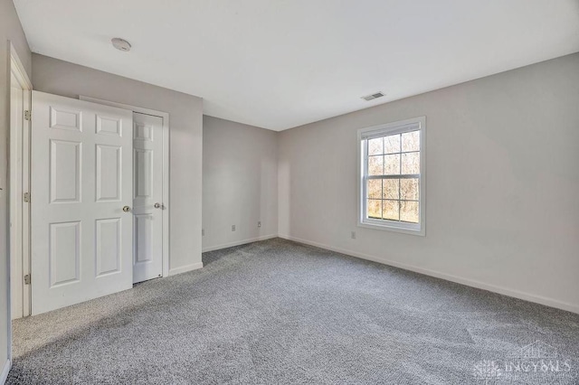 unfurnished bedroom featuring carpet floors, visible vents, and baseboards