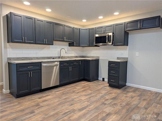 kitchen with backsplash, stainless steel appliances, light hardwood / wood-style floors, and sink