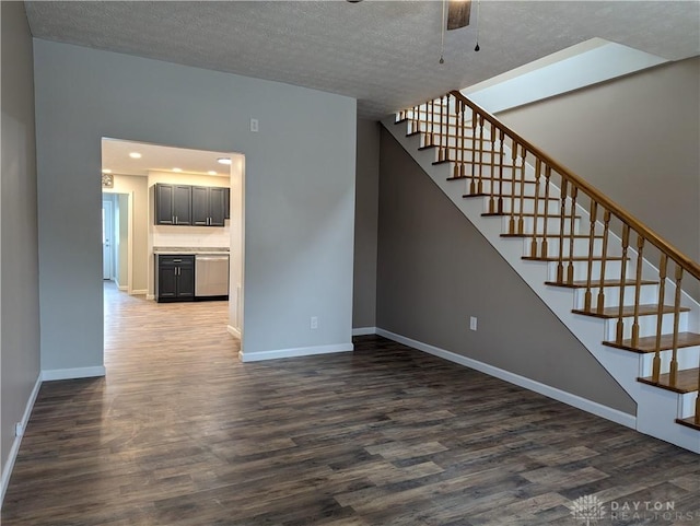 unfurnished living room with ceiling fan, dark hardwood / wood-style flooring, and a textured ceiling