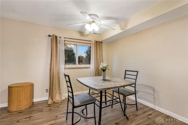 dining room with hardwood / wood-style floors, ceiling fan, and a textured ceiling