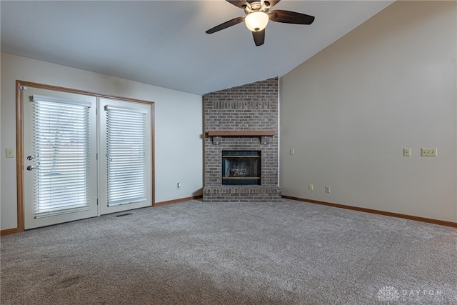 unfurnished living room featuring carpet flooring, a brick fireplace, vaulted ceiling, and ceiling fan