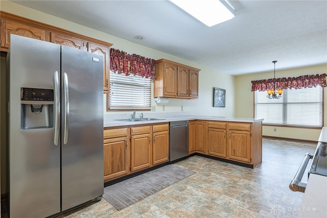 kitchen featuring kitchen peninsula, appliances with stainless steel finishes, sink, decorative light fixtures, and a notable chandelier