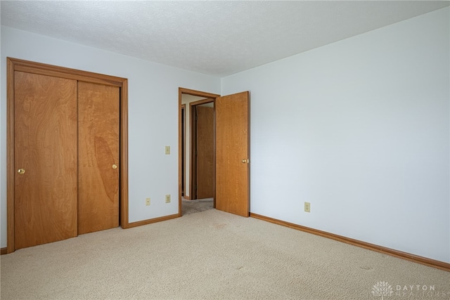 unfurnished bedroom with a closet, light colored carpet, and a textured ceiling