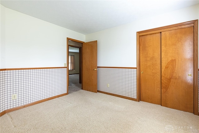 unfurnished bedroom featuring light carpet and a closet