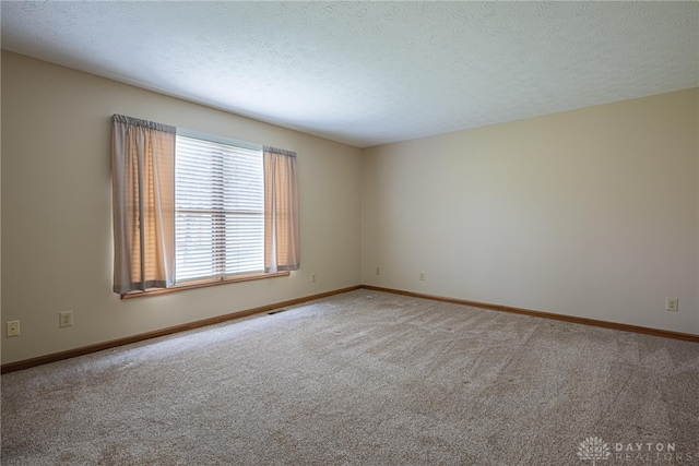 unfurnished room featuring carpet and a textured ceiling