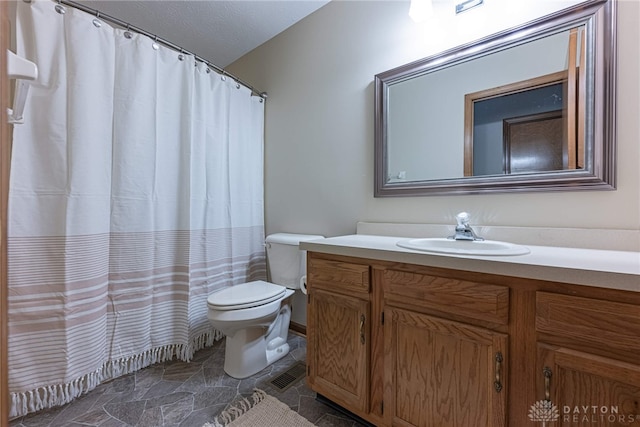 bathroom with vanity, toilet, and a textured ceiling