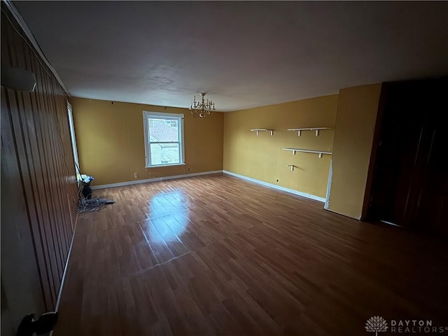 unfurnished room featuring a chandelier and dark hardwood / wood-style floors